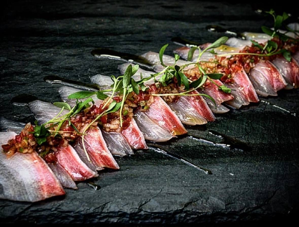 Sashimi with herb garnish on slate